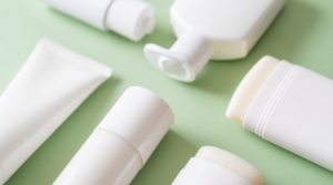 Prodotti protezione solare viso in diverse texture su sfondo verde pastello: fluido, crema, gel e stick