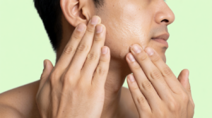 Uomo che applica olio viso prima del massaggio gua sha sulla mascella