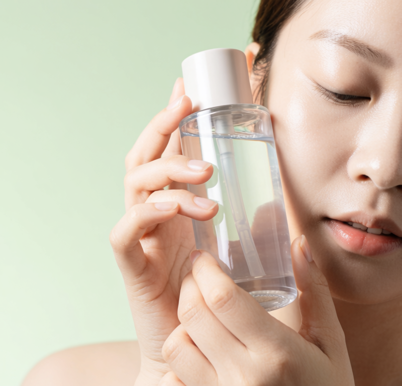 donna che tiene in mano un'essenza coreana con pelle luminosa e idratata