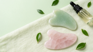Pietre gua sha in giada e quarzo rosa con olio viso su superficie in lino