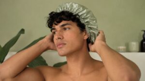 uomo con capelli ricci e cuffia in seta per la routine notturna